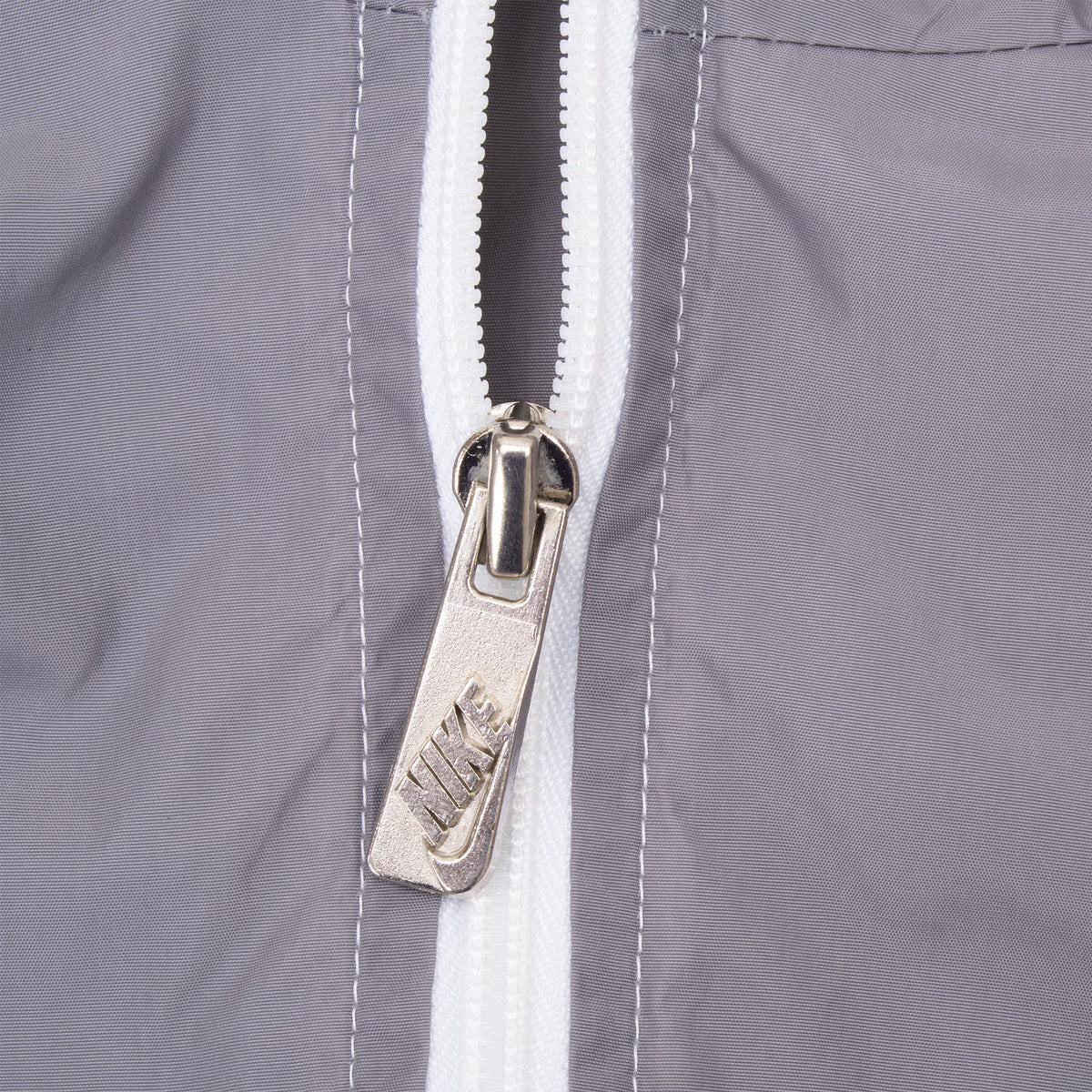 Close-up of metal Nike zipper pull on grey and white windbreaker