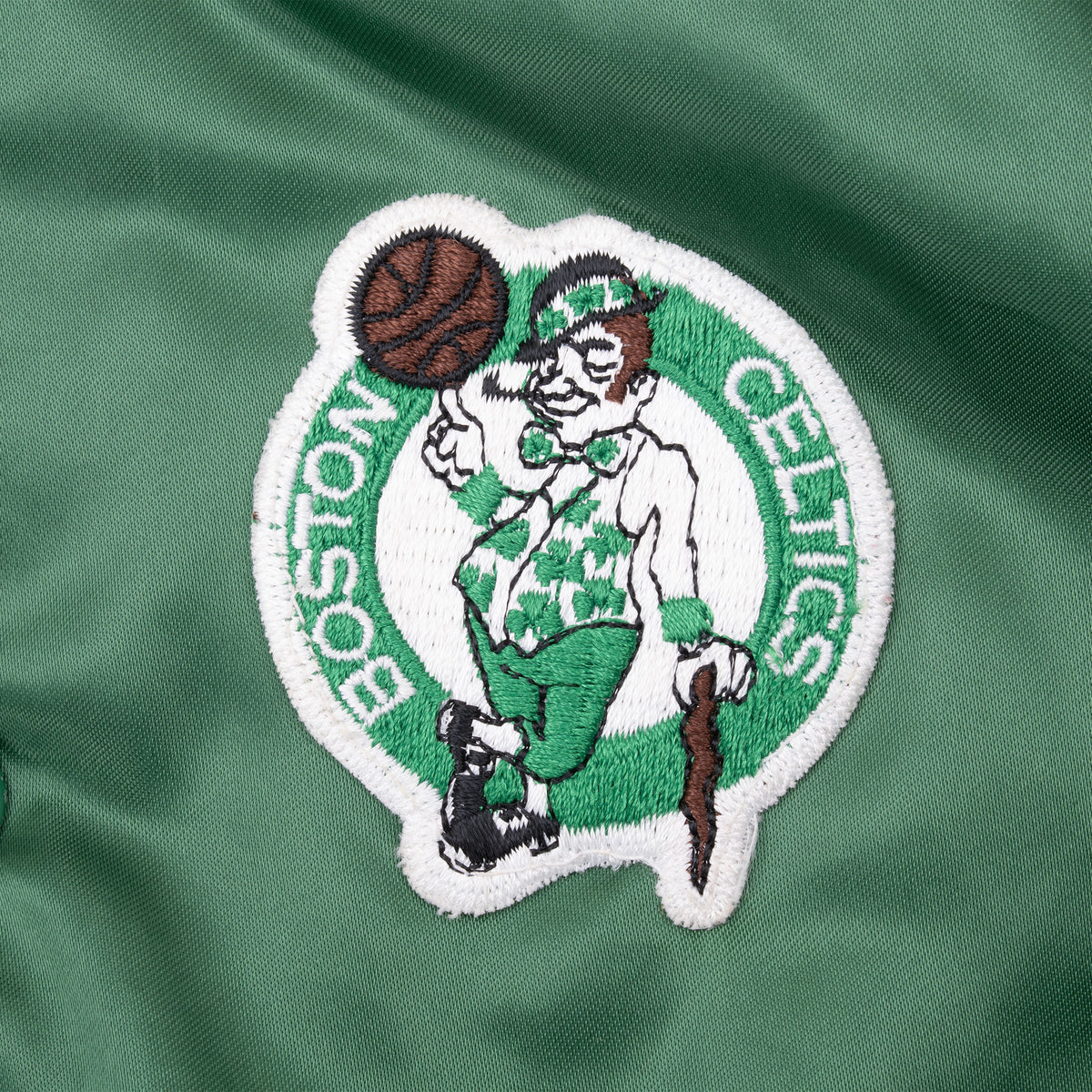 Close-up of embroidered Boston Celtics leprechaun logo patch on green satin