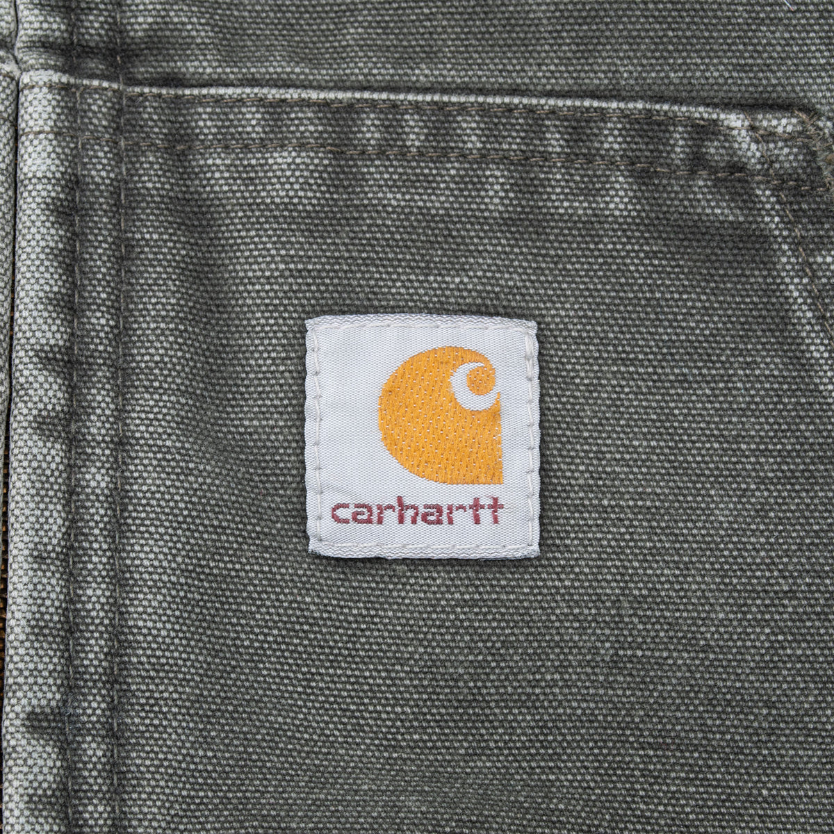 Close-up of Carhartt logo patch on the faded green front pocket