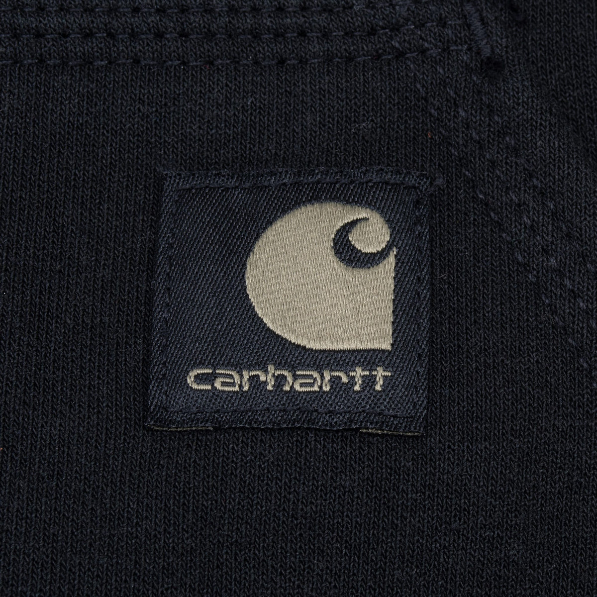 Close-up of woven Carhartt logo patch on black kangaroo pocket