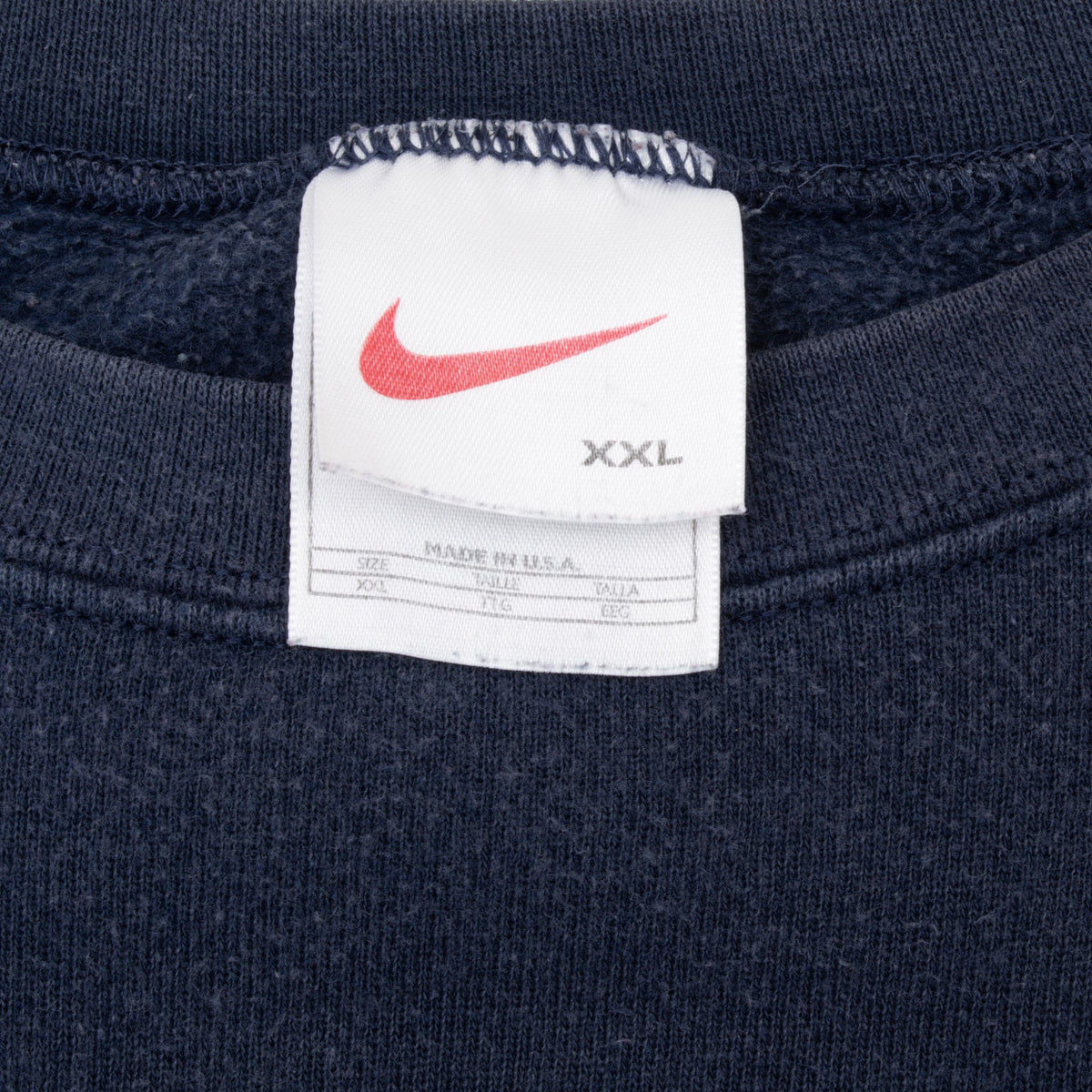 Nike neck tag with red Swoosh and XXL size marking inside blue sweatshirt