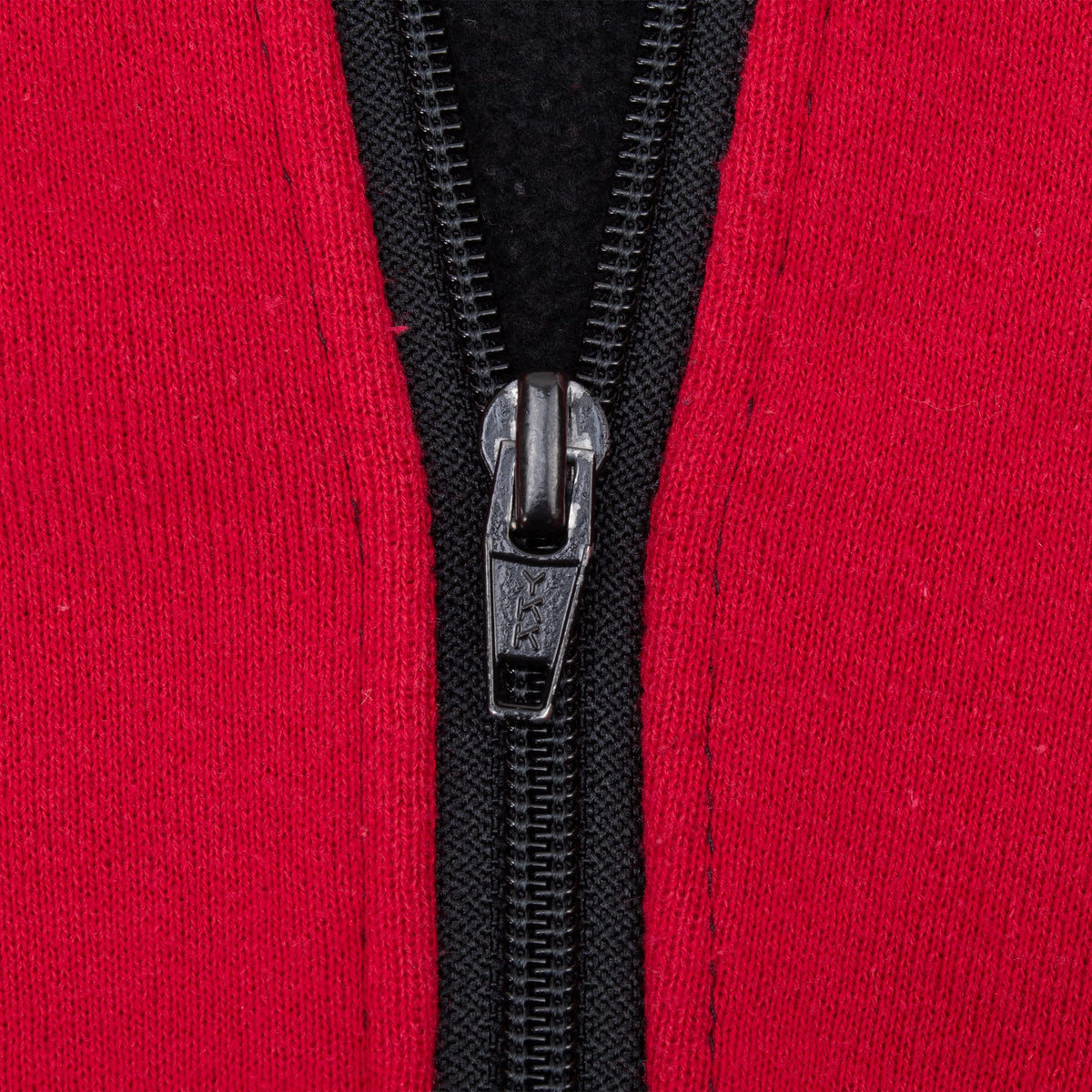 Close-up of black front zipper and Nike-branded pull against red fabric