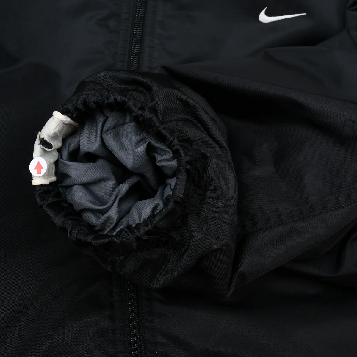 Close-up of elastic cuff and adjustable closure detail on black Nike jacket sleeve