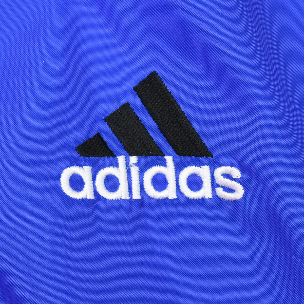 Close-up of black and white adidas chest logo embroidered on royal blue fabric