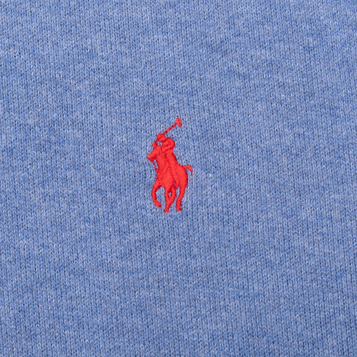Close-up of red Polo pony embroidery on blue sweater