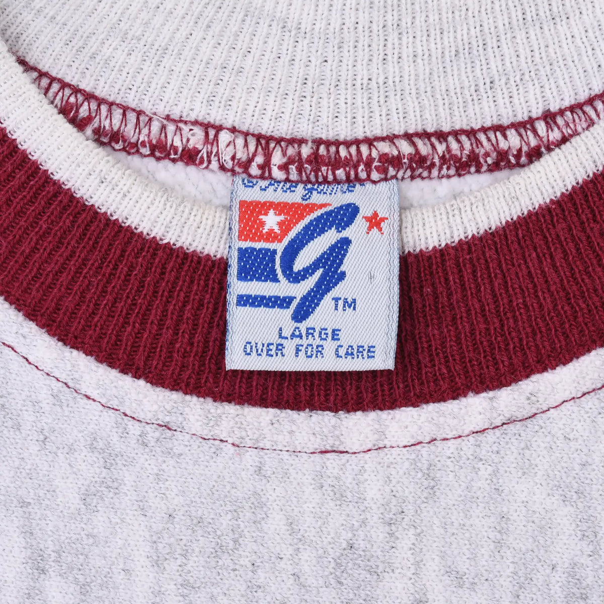 Close-up of size Large neck tag and crimson ribbed collar on gray sweatshirt