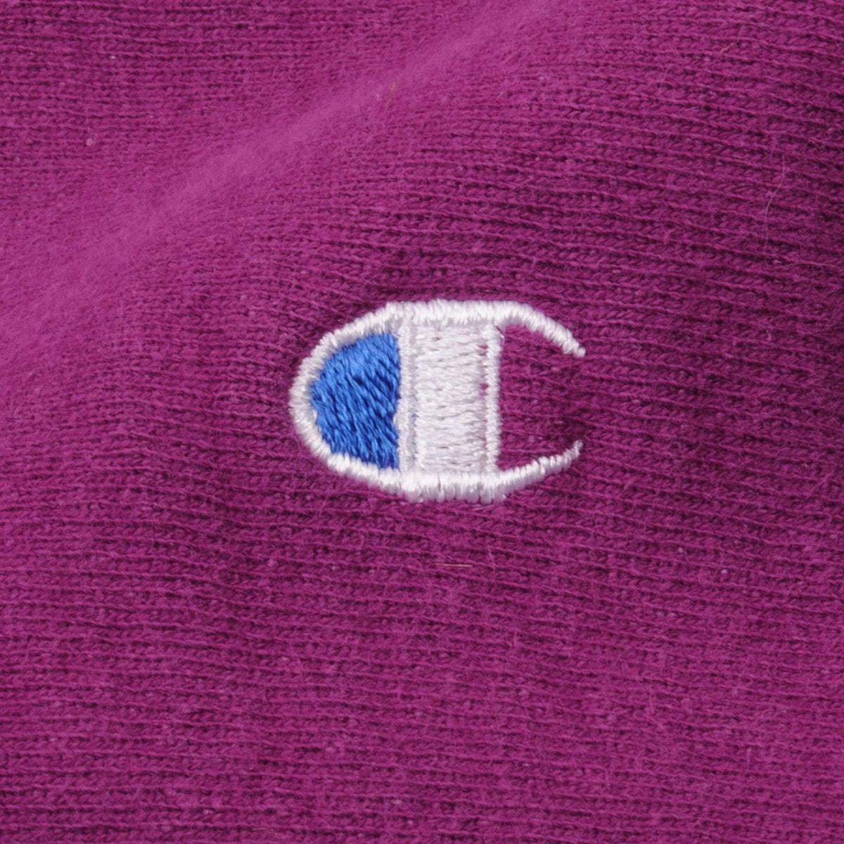 Close-up of embroidered Champion C chest logo on fuchsia sweatshirt