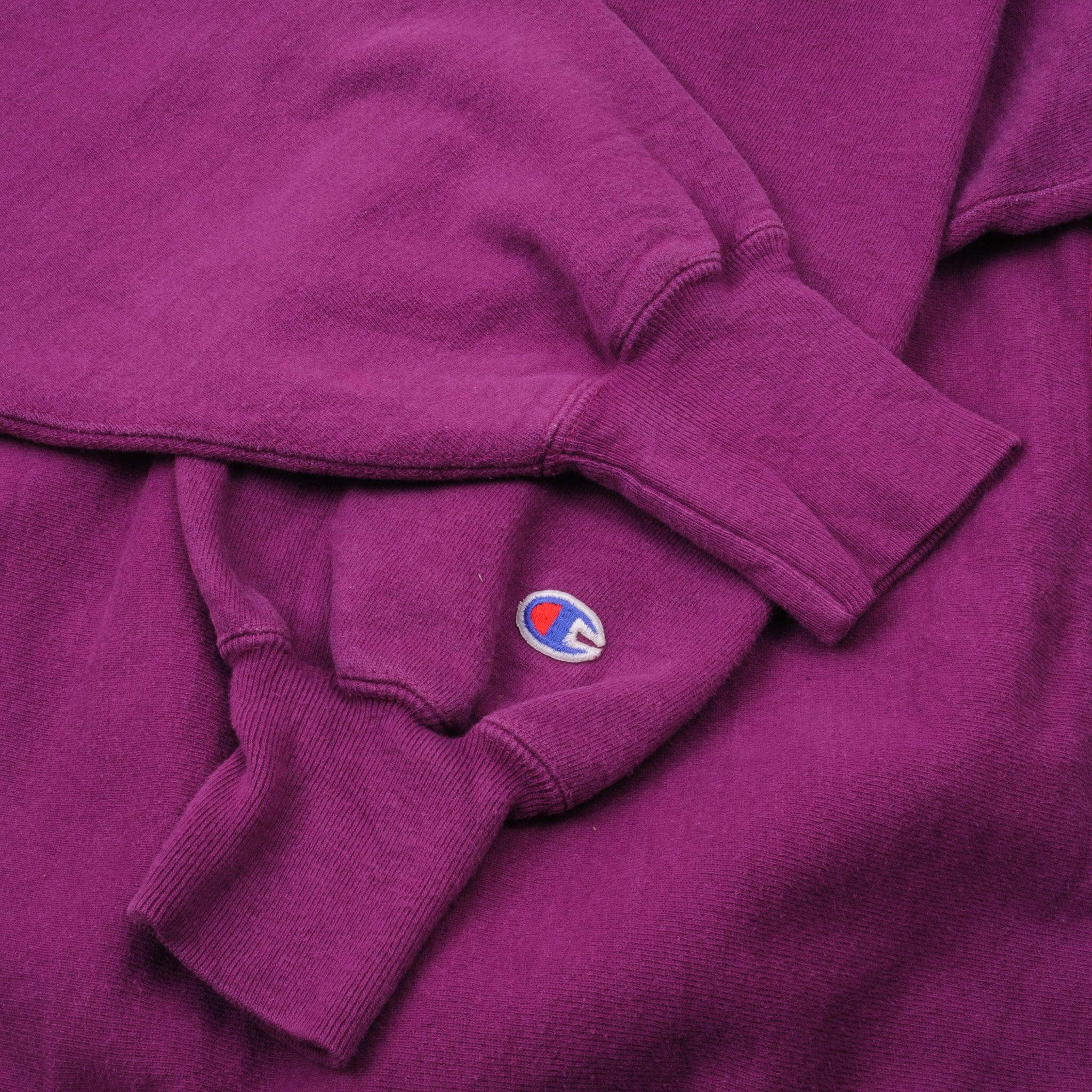 Close-up of ribbed cuffs and embroidered Champion C sleeve logo on fuchsia sweatshirt