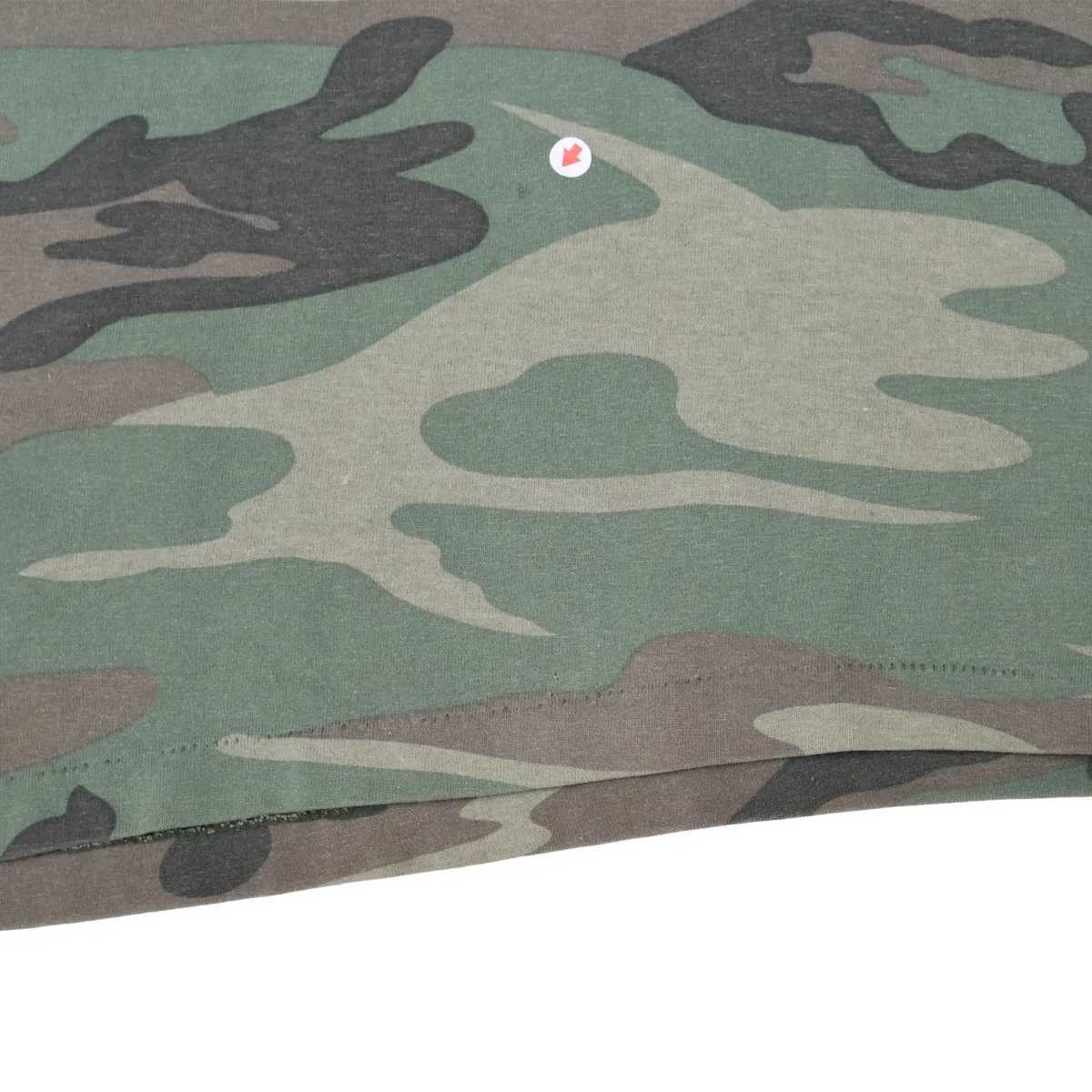 Close-up of woodland camouflage fabric and bottom hem with a small spot marked
