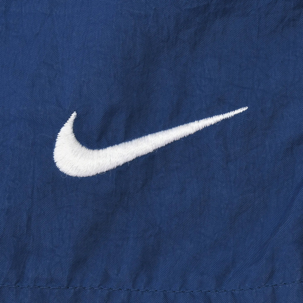 Close-up of white embroidered Nike Swoosh on navy blue fabric