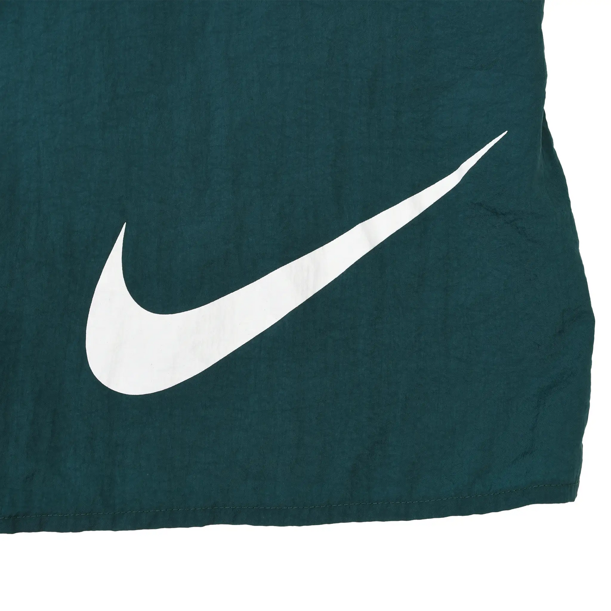 Close-up of large white Nike Swoosh print on green swim trunks