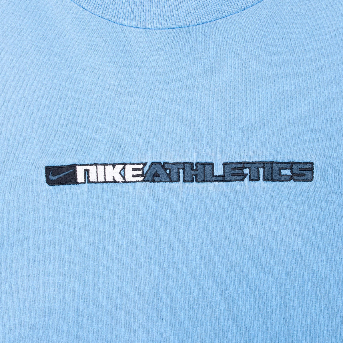 Close-up of white and dark blue Nike Athletics Swoosh embroidery on chest