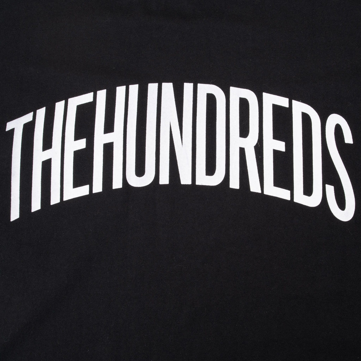 Close-up of arched white The Hundreds chest print on black fabric