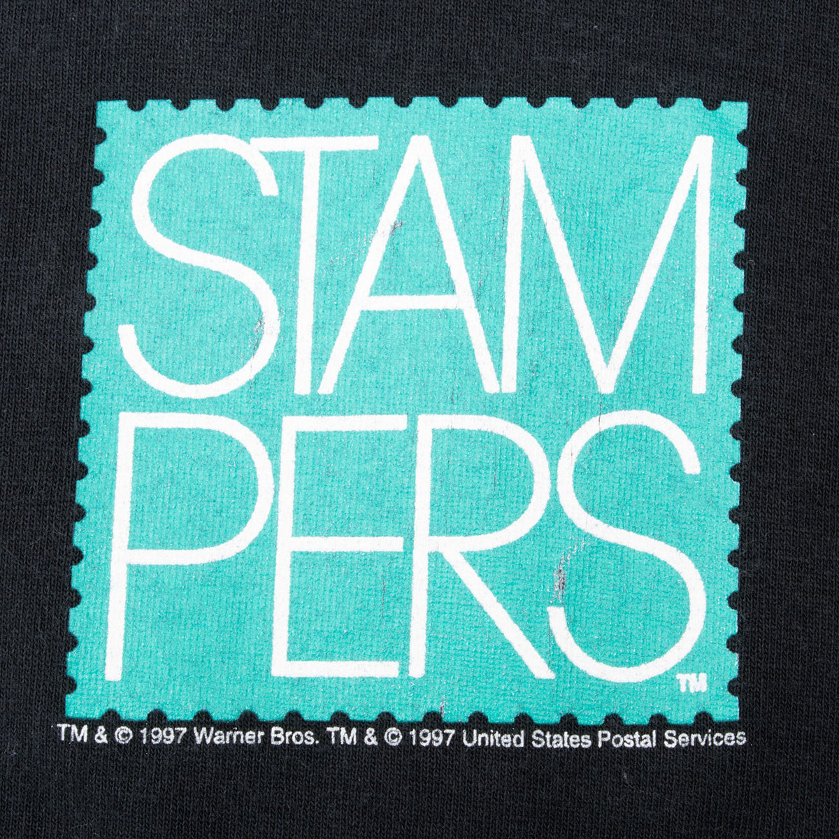 Close-up of turquoise and white Stampers chest print on black fabric