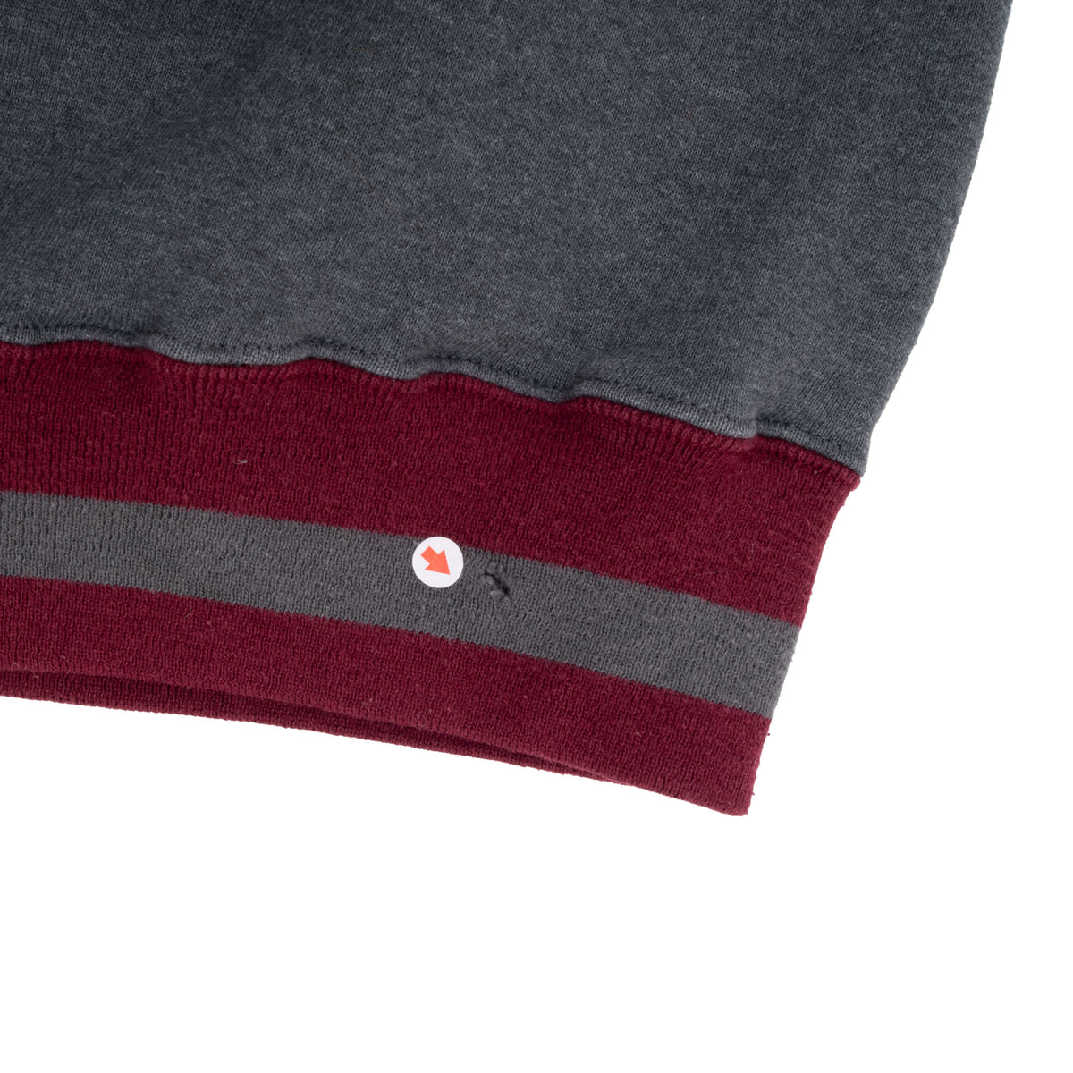Close-up of small hole in burgundy and grey striped sweatshirt hem