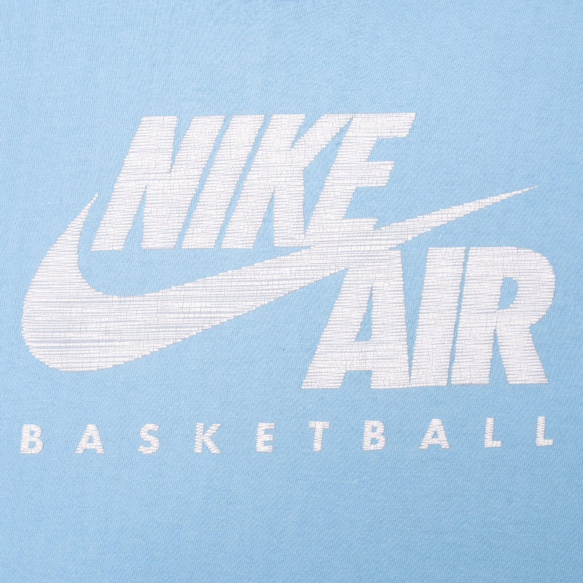 Close-up of white Nike Air Swoosh and Basketball chest print on blue fabric