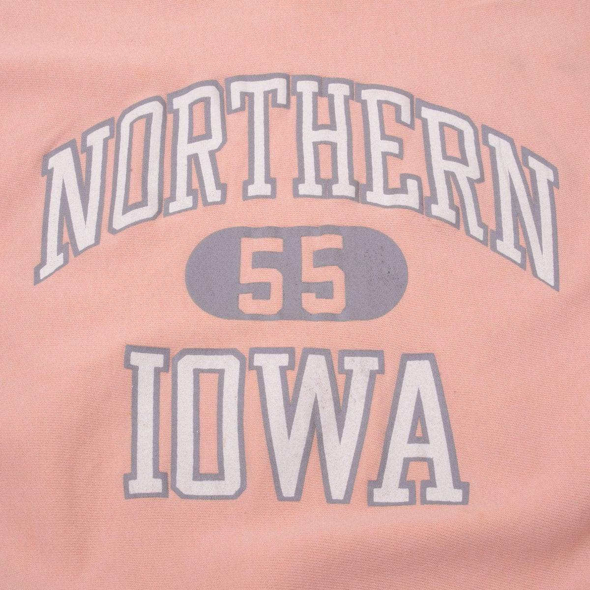 Close-up of gray and white Northern 55 Iowa chest print on pink fabric