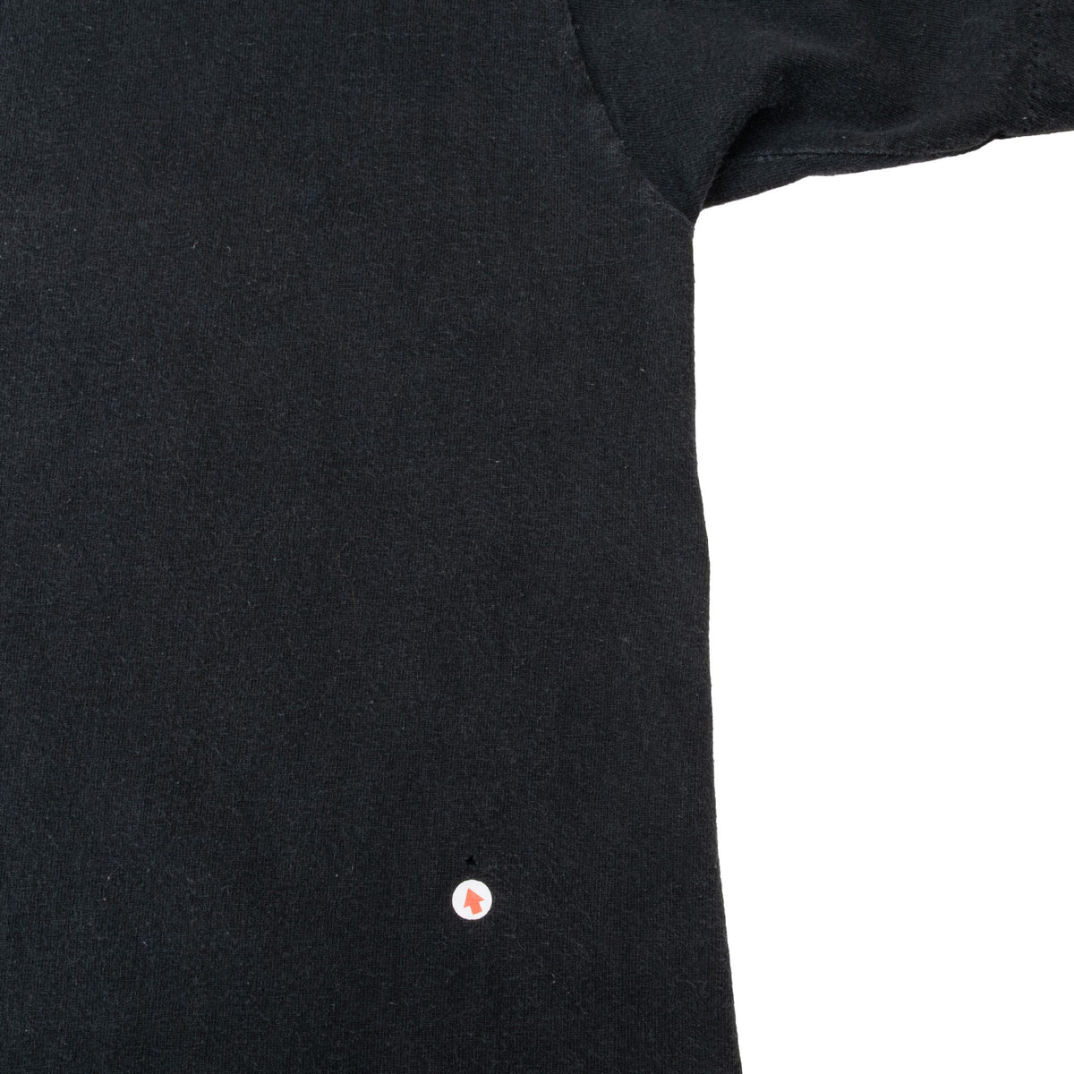 Close-up of lower black T-shirt fabric with a small spot marked near the hem