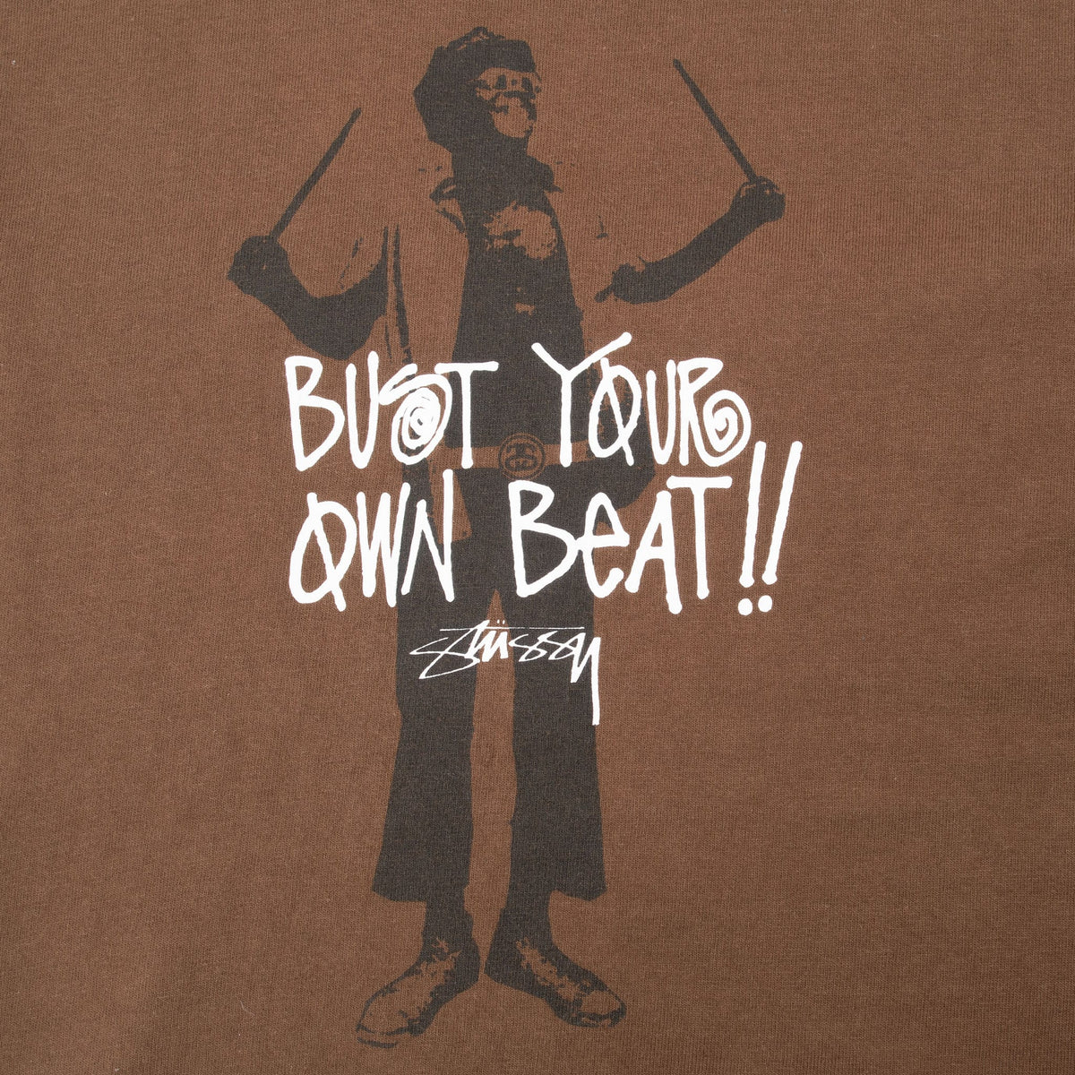 Close-up of black drummer figure, white Bust Your Own Beat lettering, and Stussy script logo