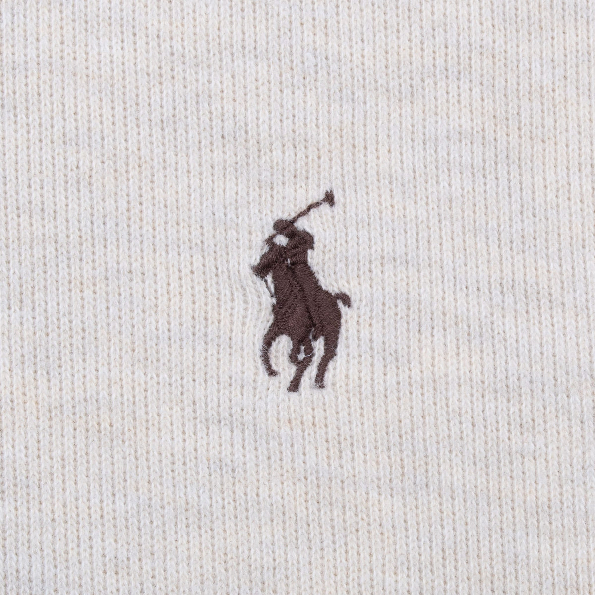 Close-up of brown embroidered Polo pony logo on beige knit fabric