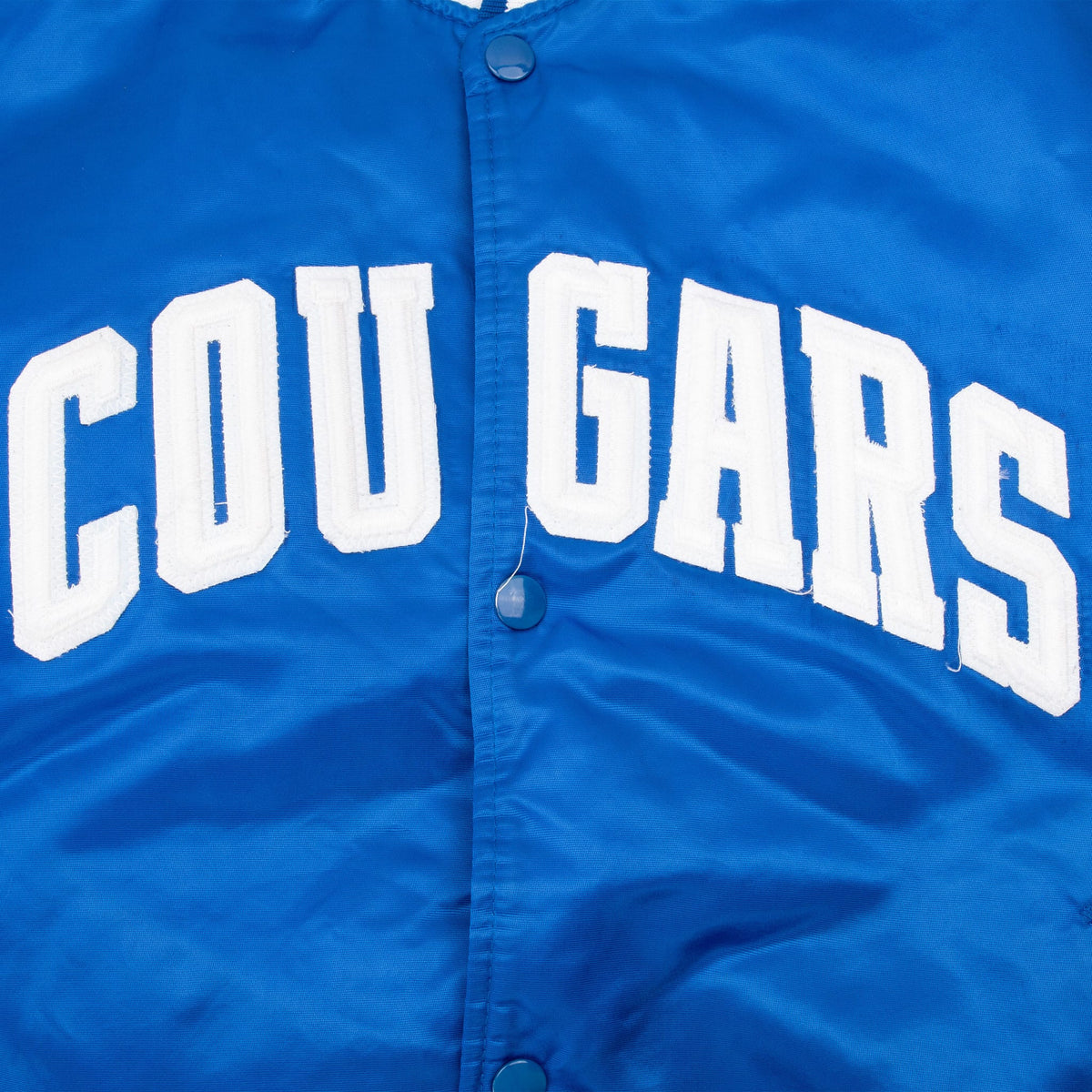 Close-up of white Cougars chest lettering and blue snap closure