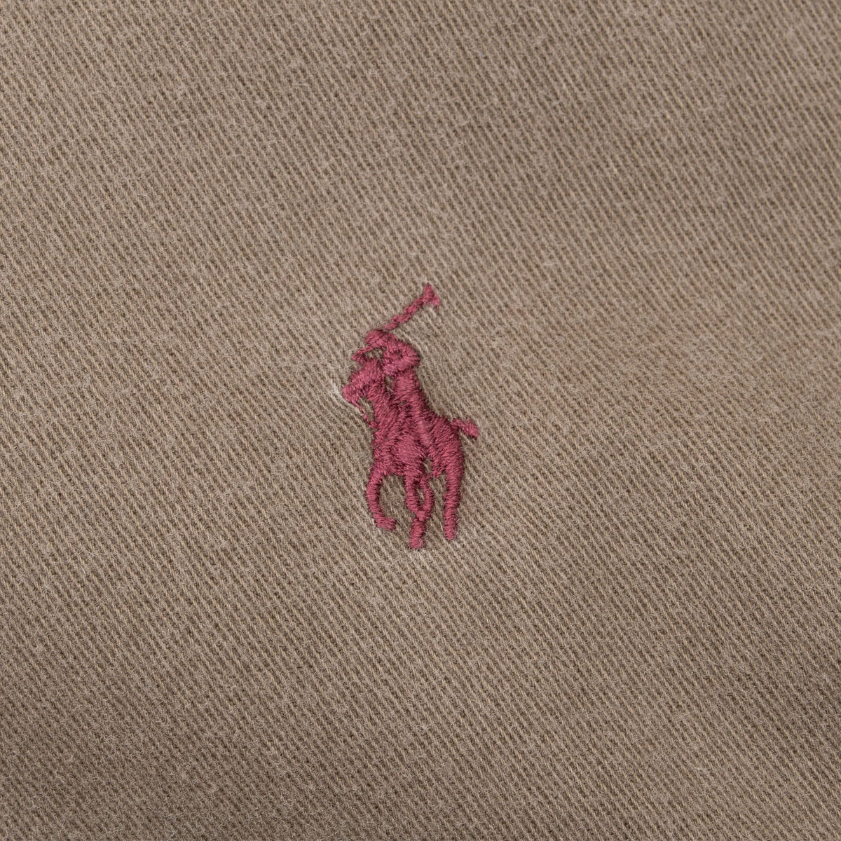 Close-up of burgundy Polo pony embroidery on khaki brown shirt chest