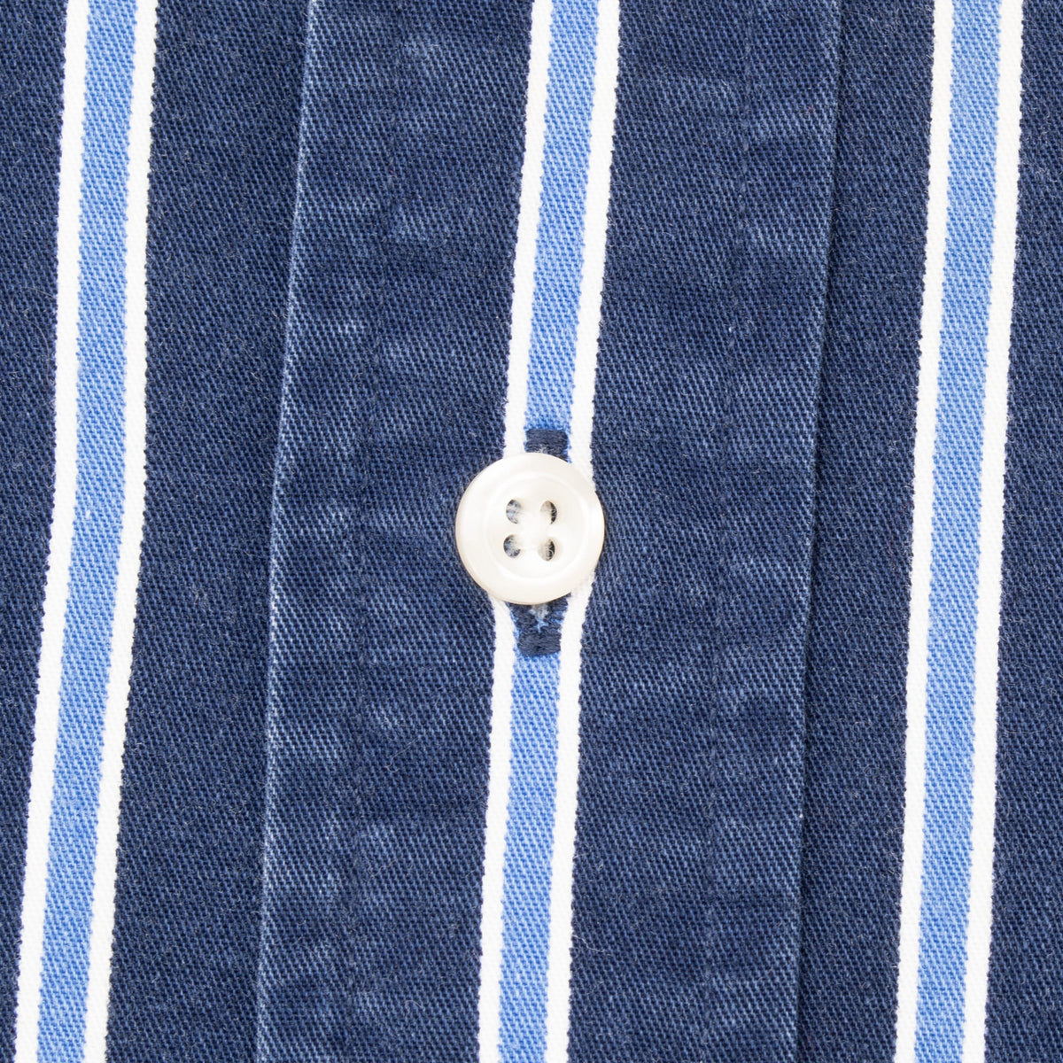 Close-up of white front button and blue and white striped fabric