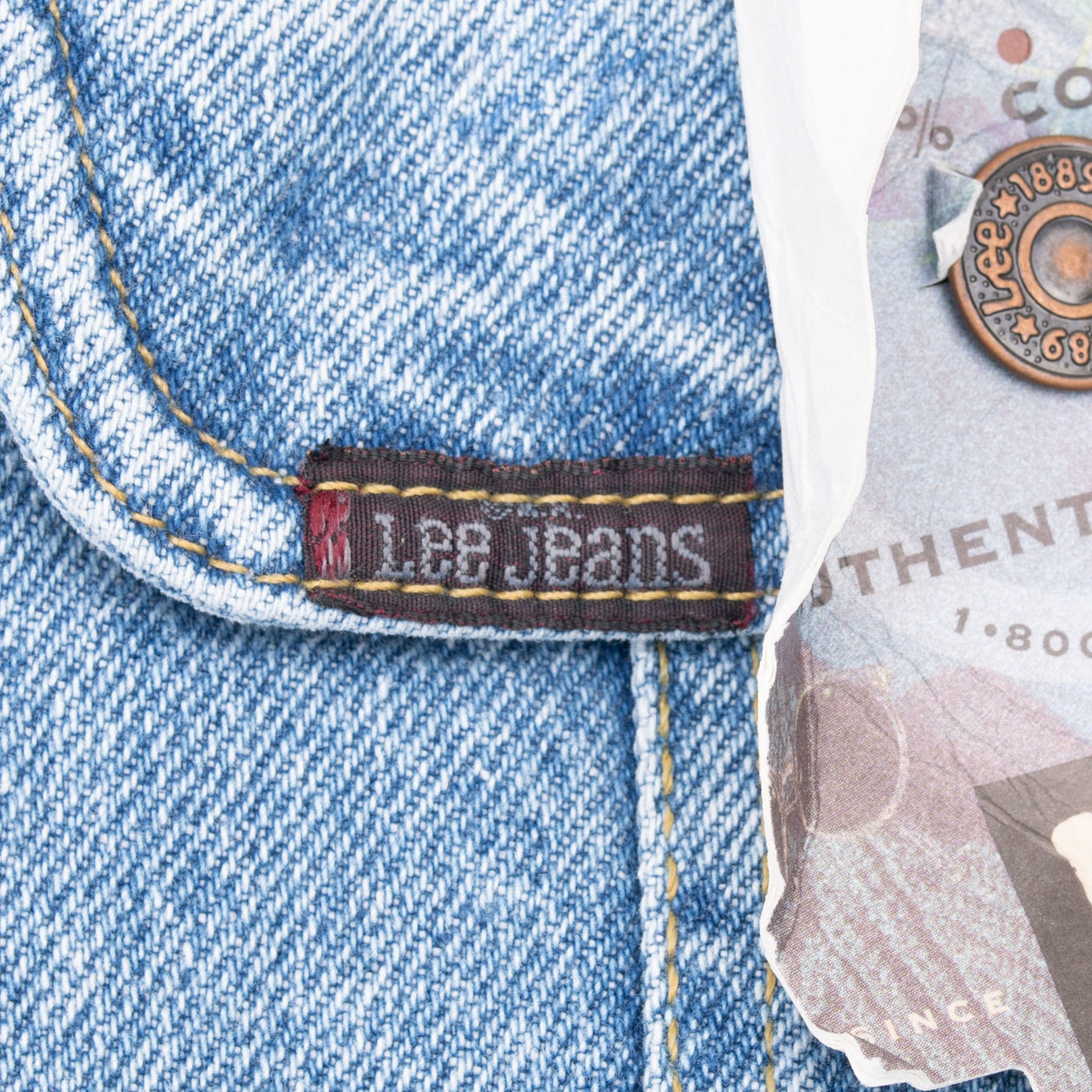 Close-up of Lee Jeans woven tab on blue denim chest pocket beside hangtag