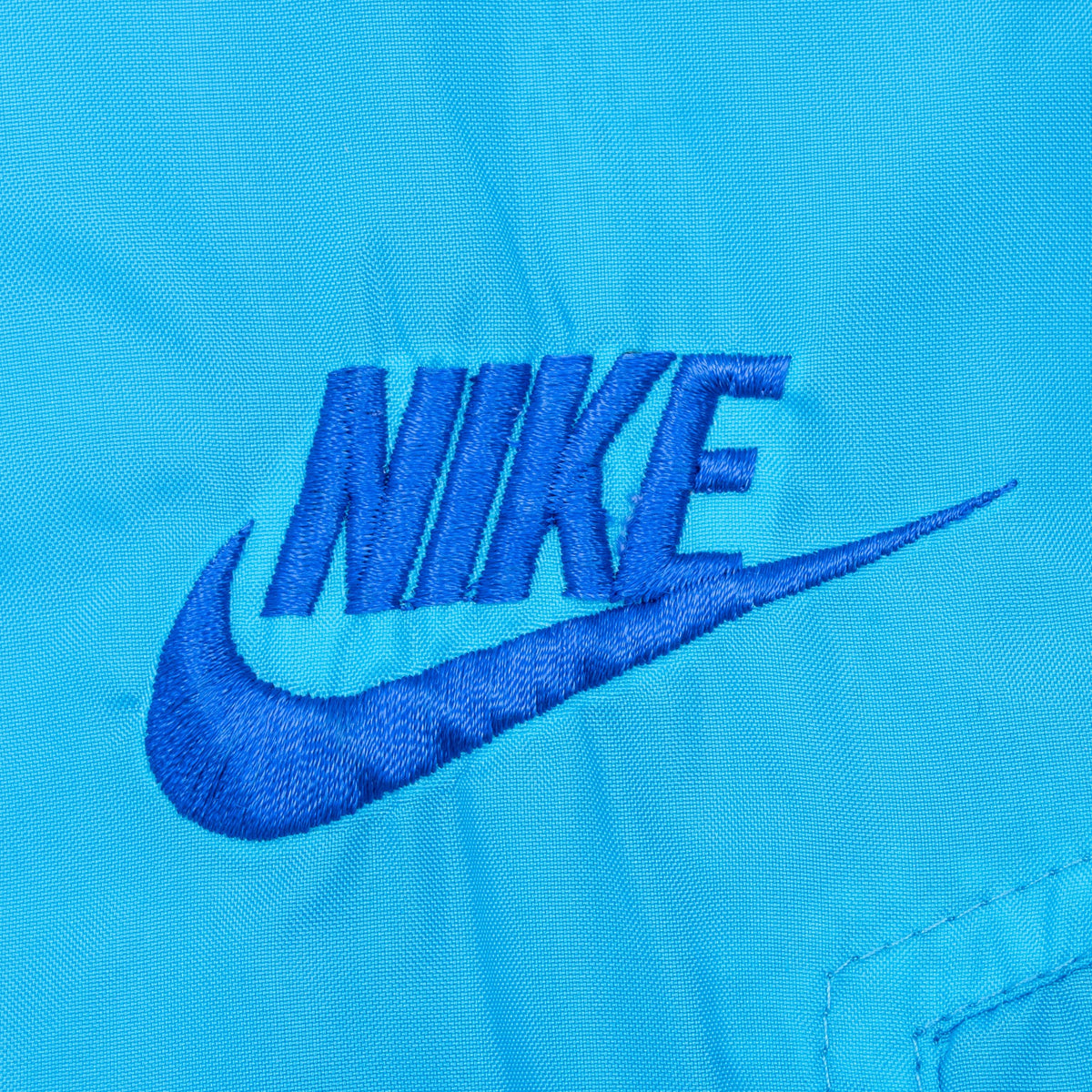 Close-up of tonal blue embroidered Nike wordmark and Swoosh on chest