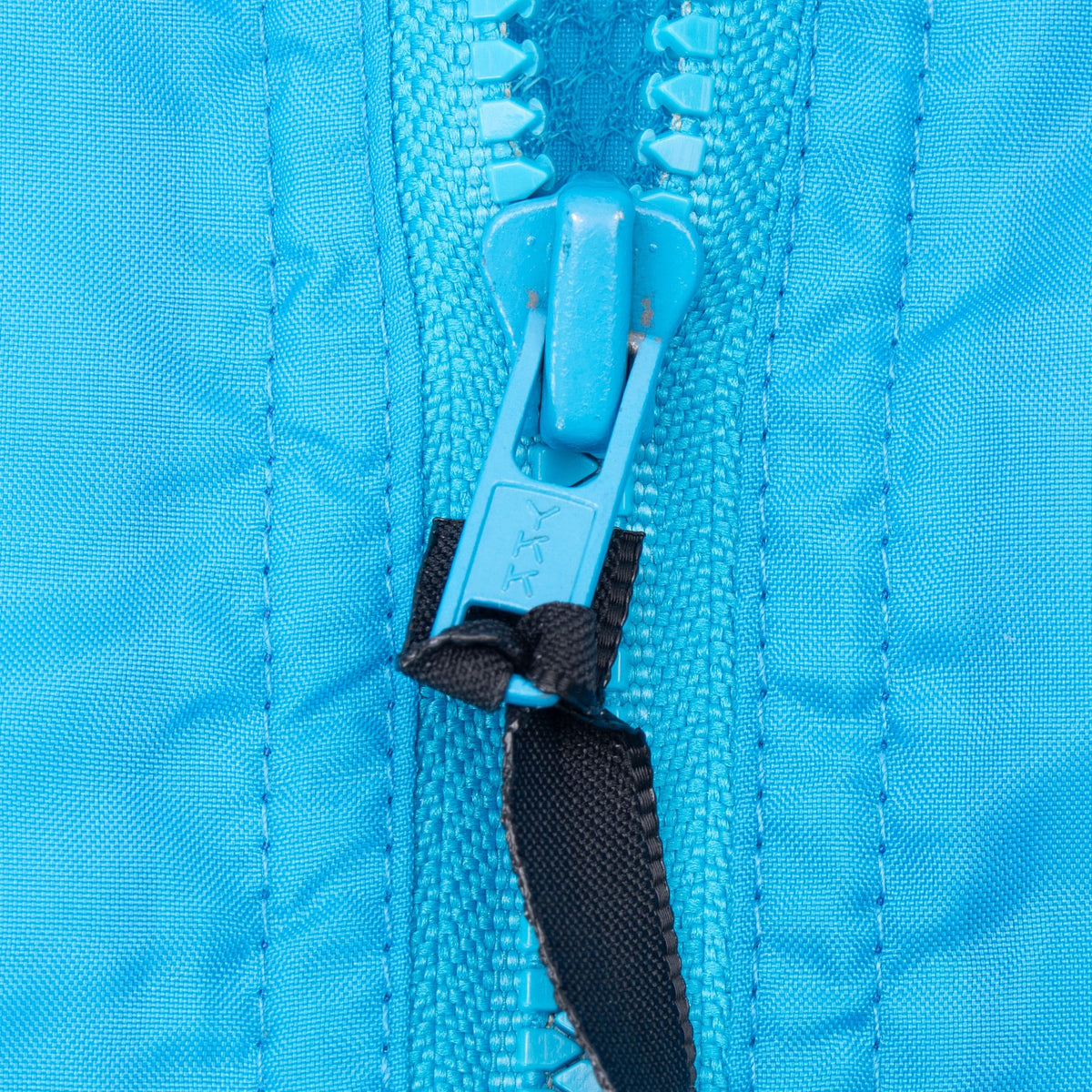 Close-up of blue YKK zipper pull with black fabric tab on Nike windbreaker