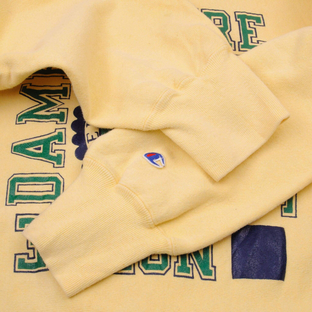 Champion sleeve logo embroidery and ribbed cuff detail on yellow sweatshirt