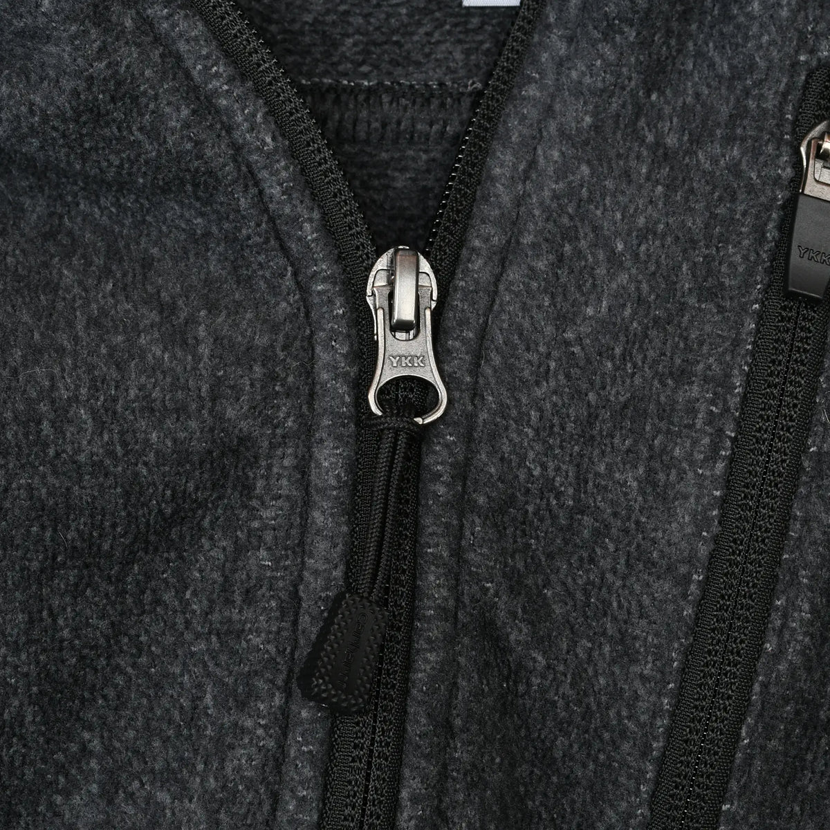 Close-up of dark grey fleece texture and YKK quarter-zip pull