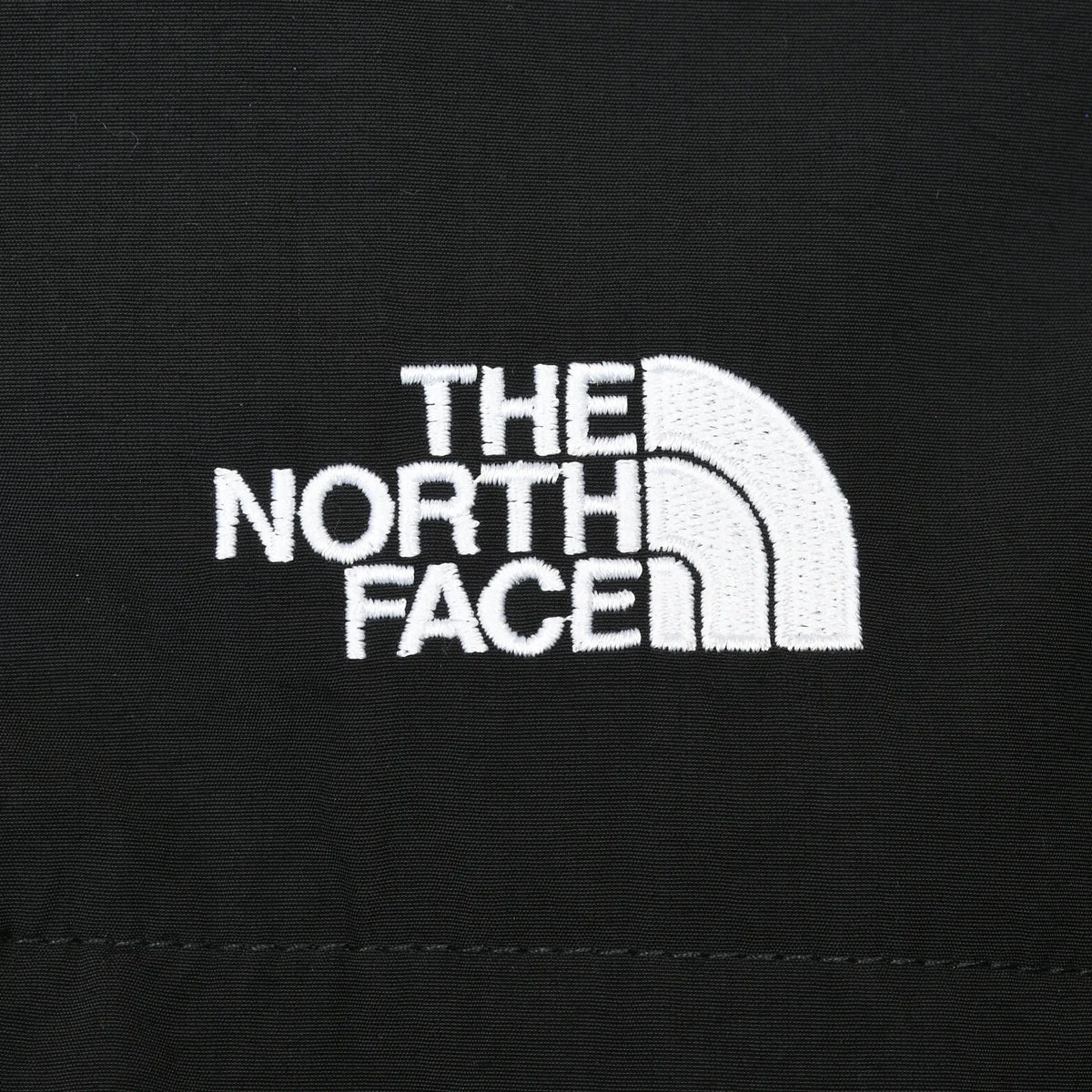 Close-up of white The North Face embroidered logo on black fabric