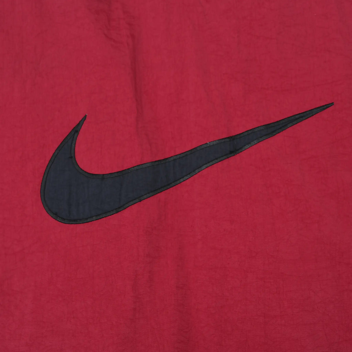 Close-up of large black Nike Swoosh applique on burgundy jacket back