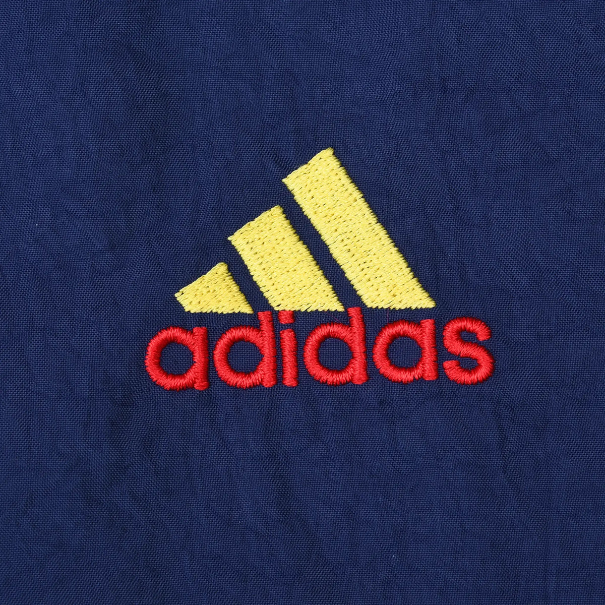 Close-up of yellow and red Adidas logo embroidery on navy fabric