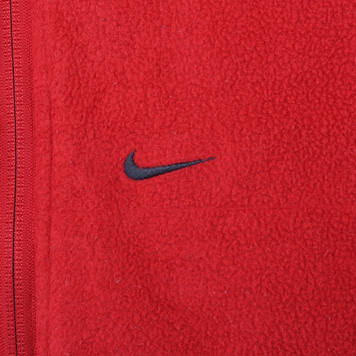 Close-up of black Nike Swoosh embroidery on red fleece