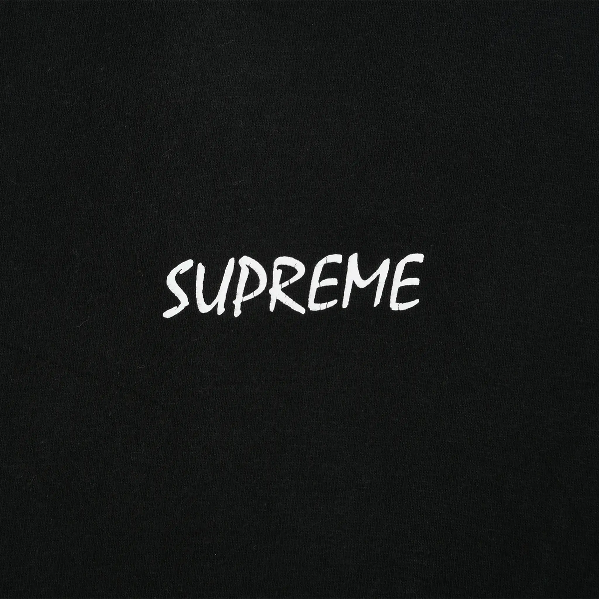 Close-up of small white Supreme script print on black fabric