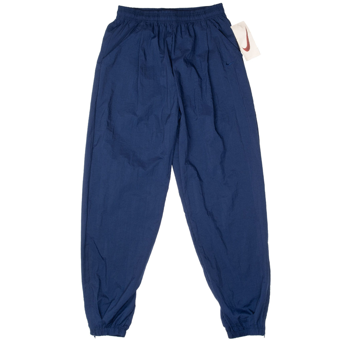 Front of blue Nike nylon track pants with elastic waist, cuffs, and attached Swoosh tag