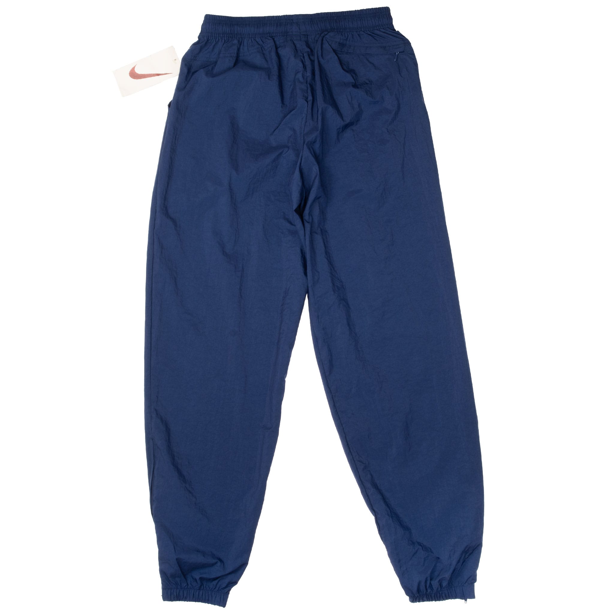 Back of blue Nike nylon track pants with rear zip pocket, elastic waist, and cuffs