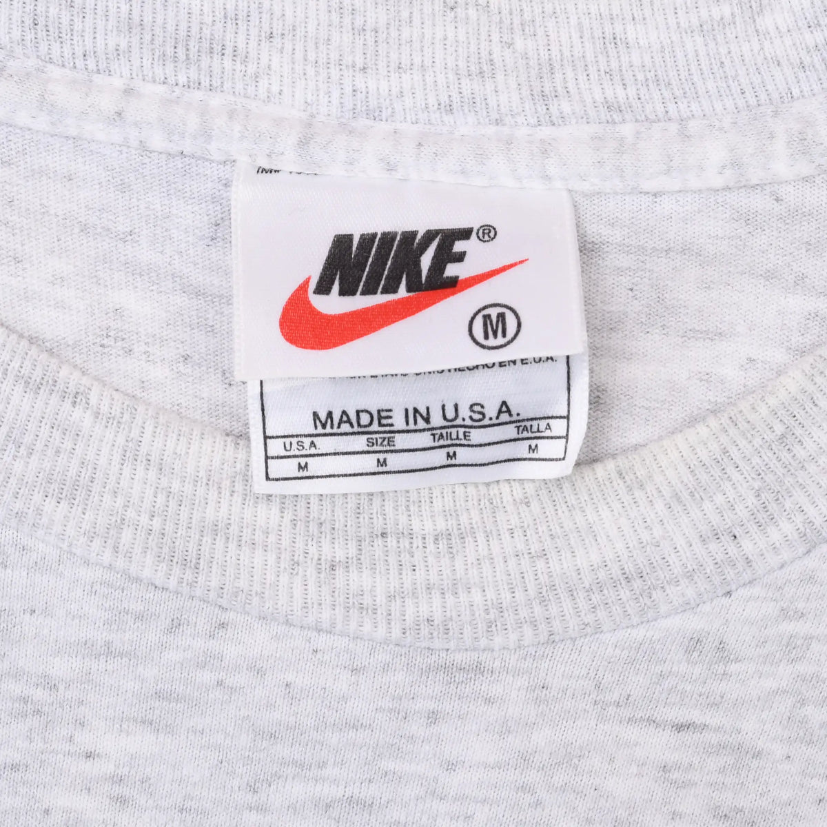 Nike medium neck tag with red Swoosh and Made in U.S.A. label on grey T-shirt