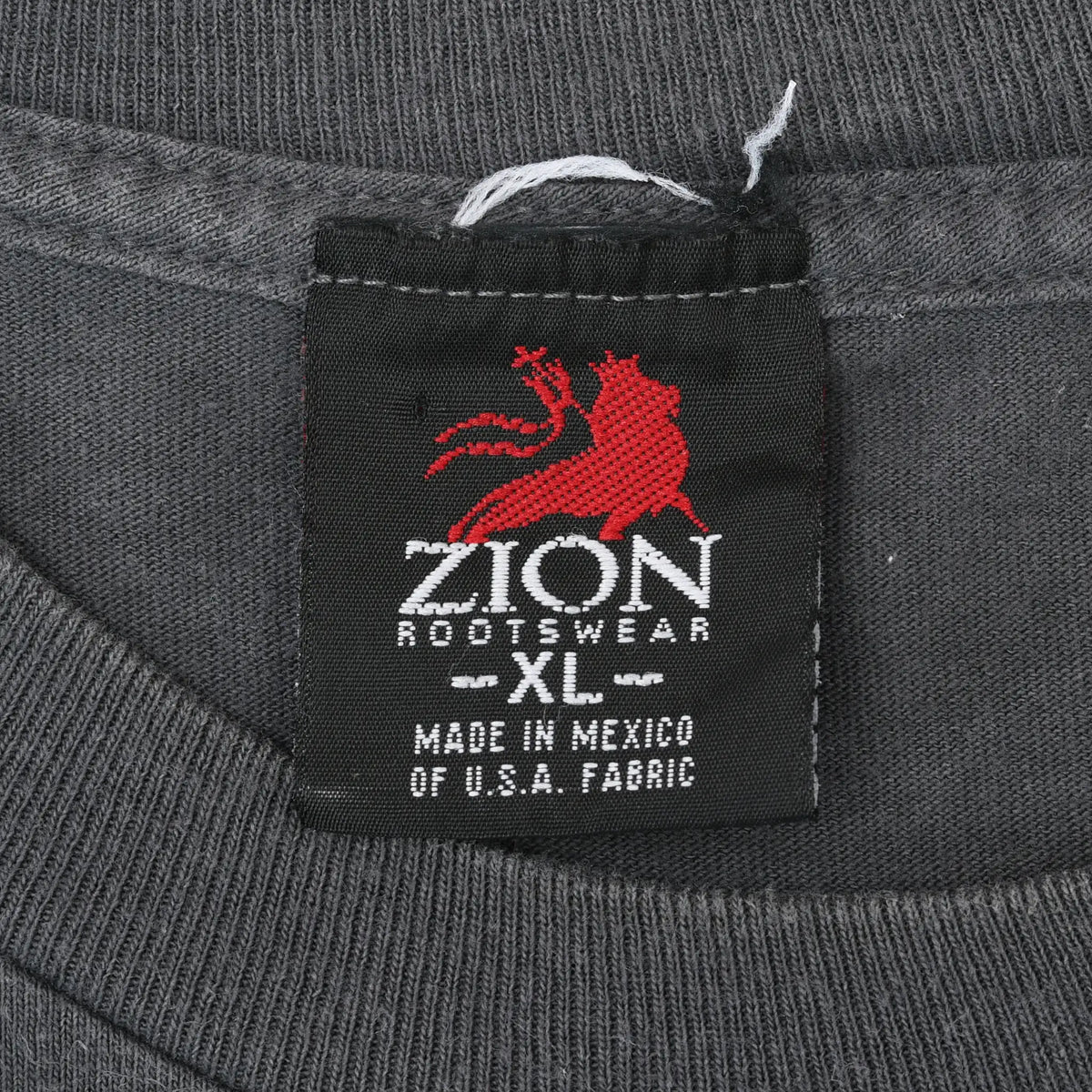 Close-up of black Zion Rootswear XL neck tag with red lion logo