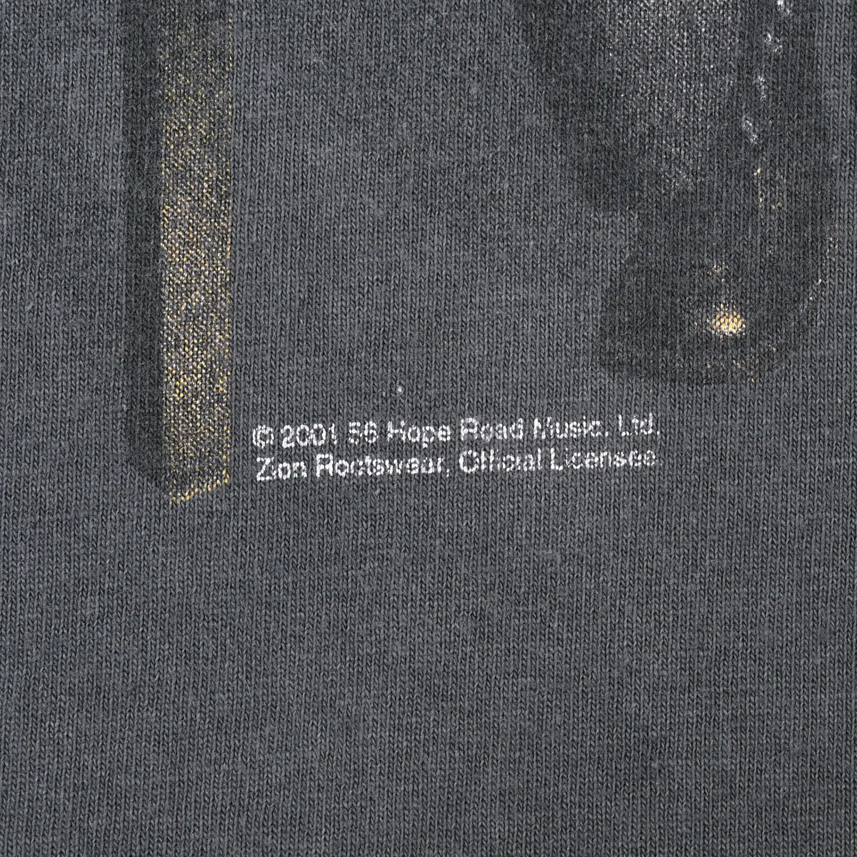 Close-up of small 2001 Bob Marley licensing copyright text printed on grey fabric