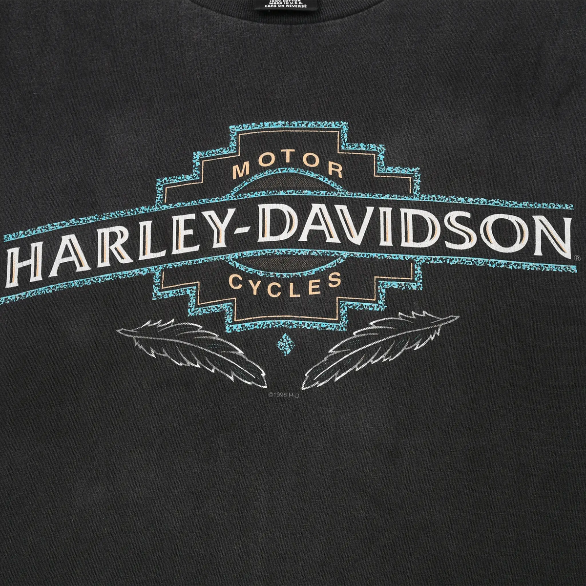 Close-up of turquoise, white, and tan Harley-Davidson Motor Cycles front print with feather details