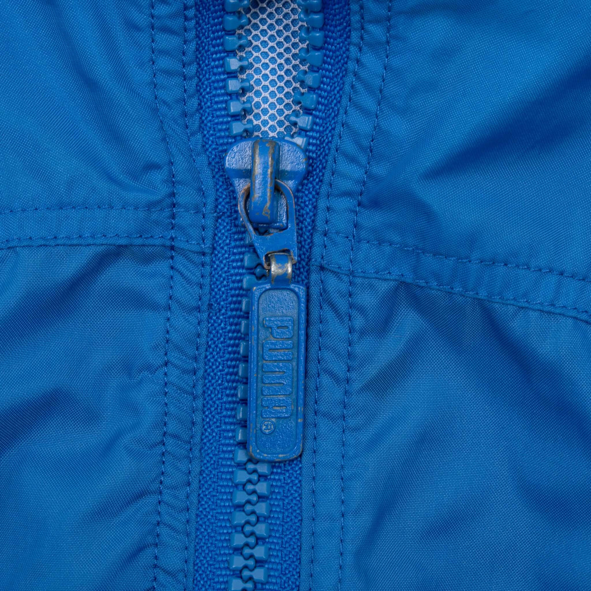 Close-up of blue front zipper with Puma-branded pull