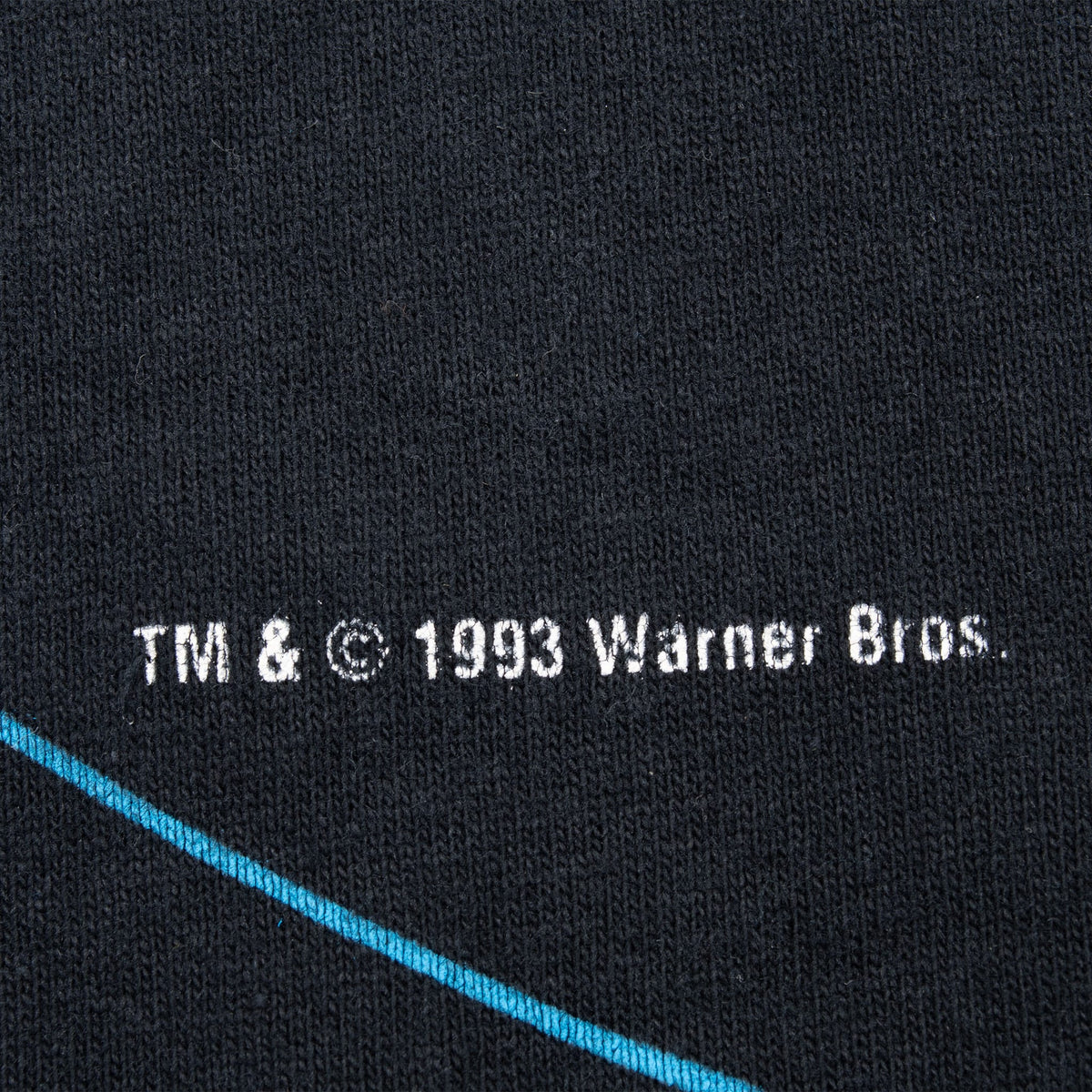 Close-up of 1993 Warner Bros. copyright text printed on black fabric