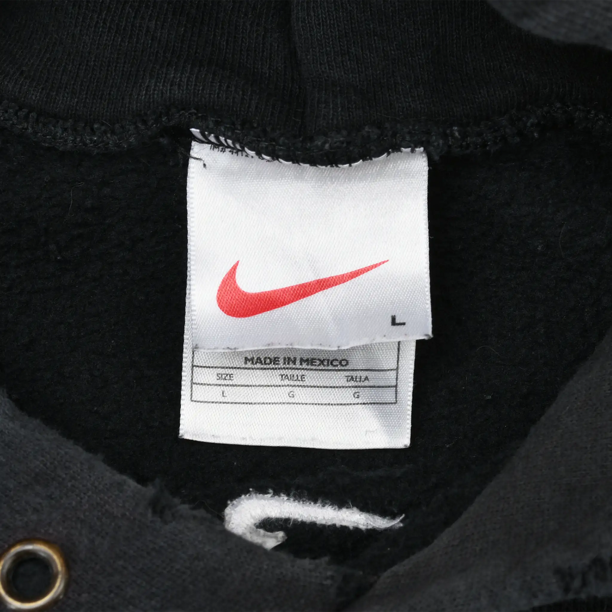 Close-up of white Nike neck tag with red Swoosh and L marking inside black hoodie