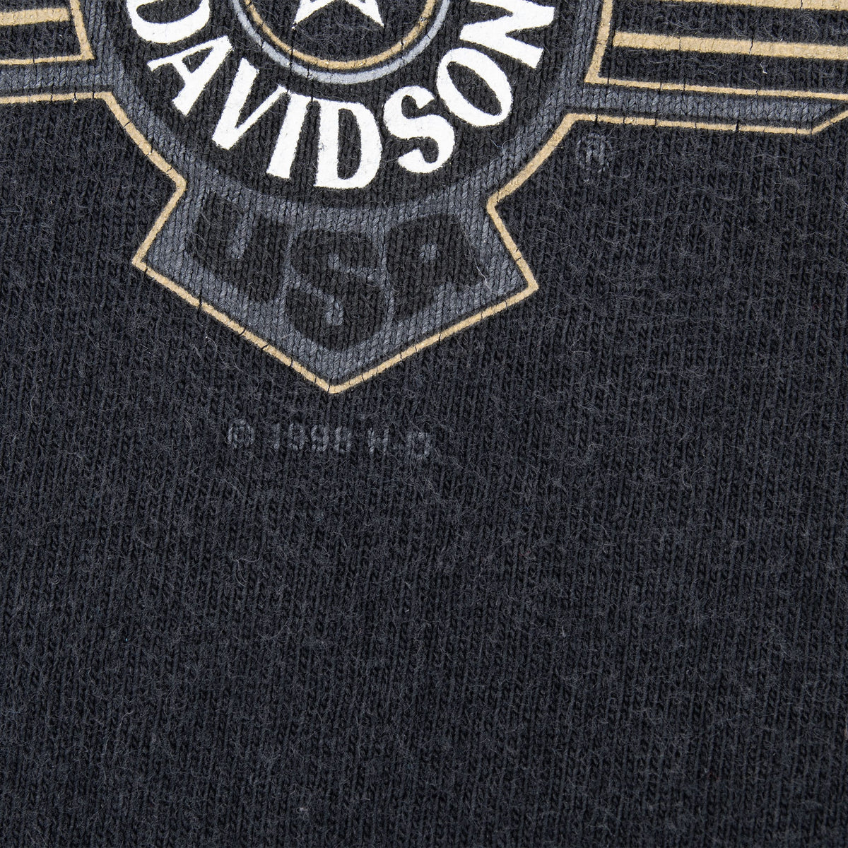 Close-up of faint USA lettering below the Harley-Davidson emblem on black fabric