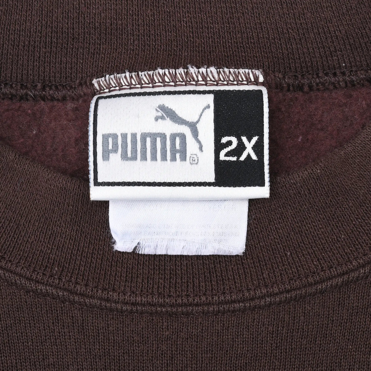 Close-up of Puma 2X neck tag inside brown sweatshirt