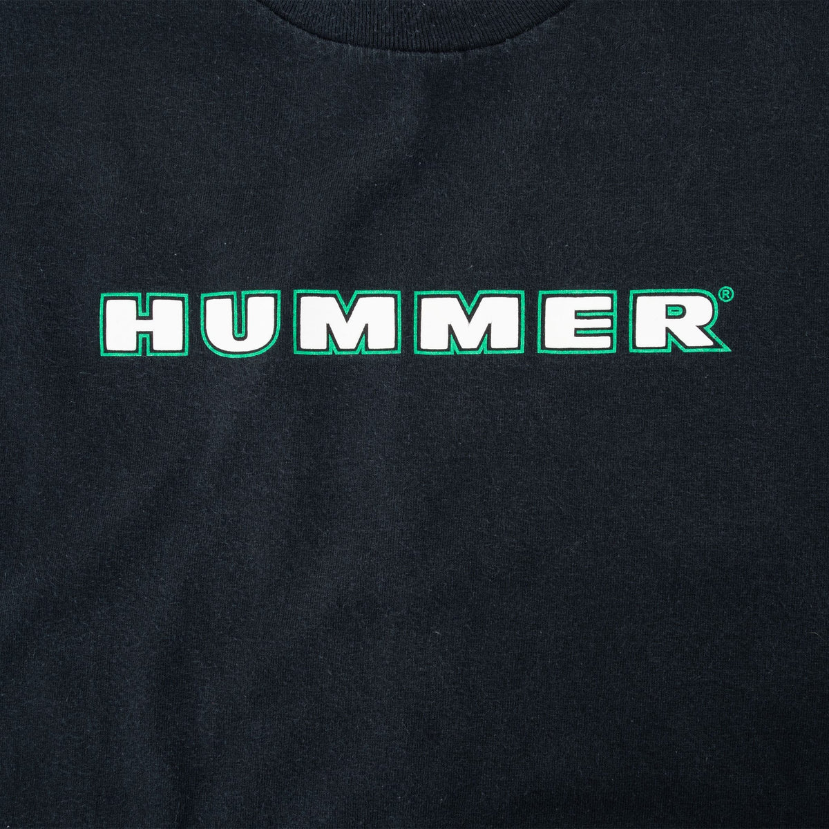 Close-up of white Hummer chest logo with green outline on black fabric