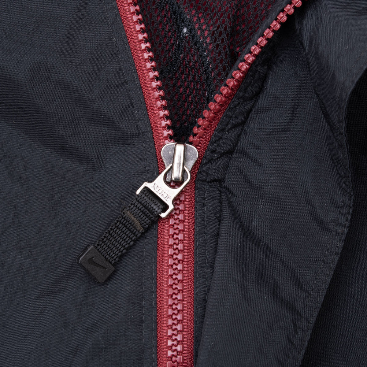 Close-up of burgundy front zipper and Nike Swoosh pull tab
